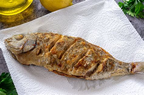 Detalle de pescado frito dorado y crujiente sobre papel absorbente