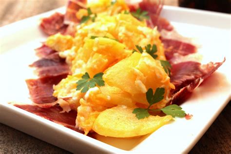 Plato de gratin de patatas con jamón ibérico recién salido del horno