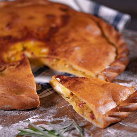 Empanada de bacalao recién horneada sobre una mesa de madera