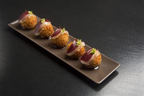Croquetas de ajo negro y jamón ibérico emplatadas