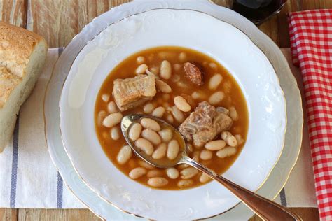 Plato tradicional de alubias con manitas de cerdo servido en un cuenco de barro