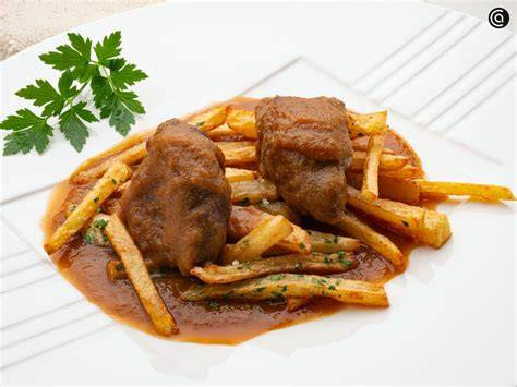 Carrilleras de cerdo asadas con tomates cherry y patatas fritas