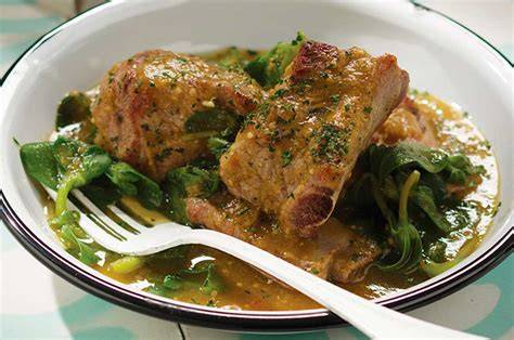 Plato servido de costillas de cerdo con salsa verde y verdolagas