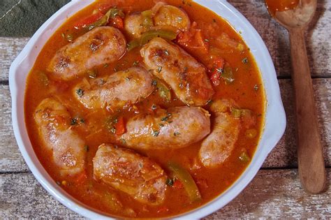 Chorizo a la pomarola en una cacerola con salsa de tomate