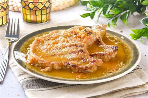Chuletas de cerdo marinándose en un recipiente con especias y vinagre
