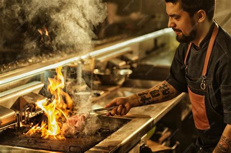 Chef cocinando en una parrilla de carbón profesional con llamas