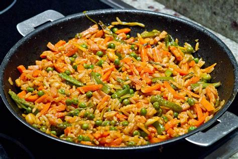 Paellera con arroz y verduras en proceso