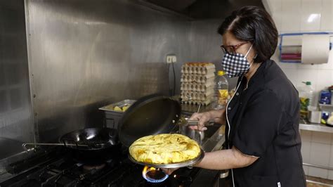 Evangelina Rey sacando una tortilla del fuego