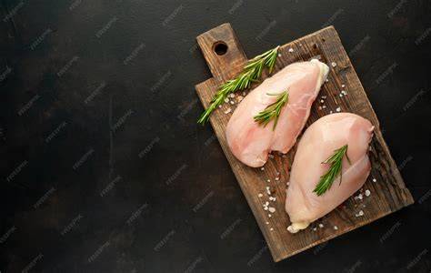 pechuga de pollo cruda sobre una tabla de madera con especias