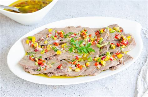 Plato de lengua a la vinagreta servido con perejil y vegetales frescos