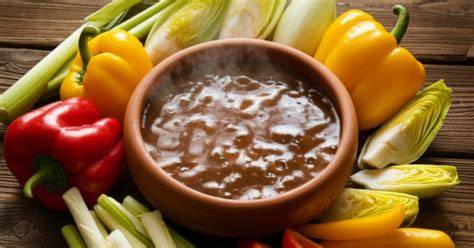 Bagna cauda servida en una cazuela de barro con vela