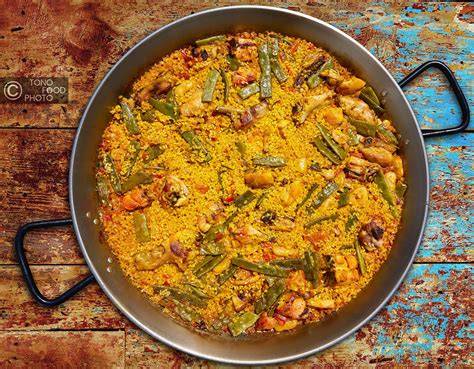 Carne de pollo y conejo dorándose en una paellera