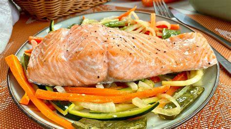 Filetes de salmón horneándose en una bandeja con verduras