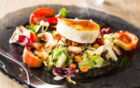 Ensalada terminada con rulo de cabra gratinado y frutos rojos