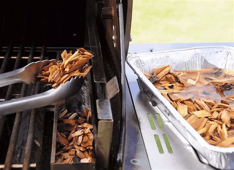 Persona añadiendo astillas de madera remojadas al carbón para ahumar