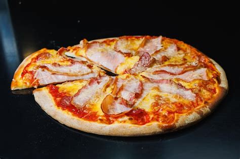 Pizza recién horneada con jamón, queso y tomate