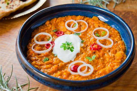 Plato de dhal de lentejas rojas servido con cilantro fresco