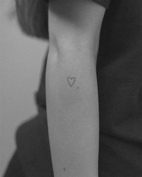 Primer plano de un tatuaje de corazón minimalista en la muñeca