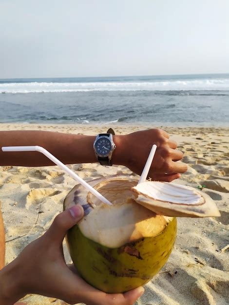Persona bebiendo agua de coco en la playa