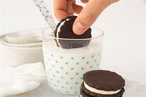 Galletas Oreo tradicionales apiladas con un vaso de leche.