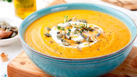 Un bol humeante de crema de calabaza y jengibre, decorado con unas semillas de calabaza tostadas.