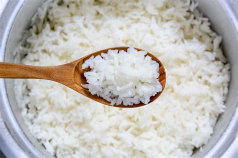 Arroz cocido en un bol con una cuchara de madera sobre un suelo de cemento negro