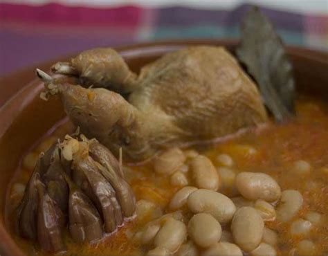 Plato de cuchara tradicional de codornices con alubias servido en cazuela de barro