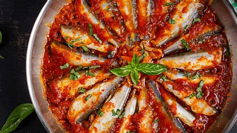 Plato de sardinas en escabeche a la catalana decorado con hierbas aromáticas y rodajas de tomate