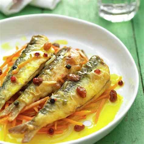 Mesa preparada con sardinas en escabeche, pan crujiente y una copa de vino blanco