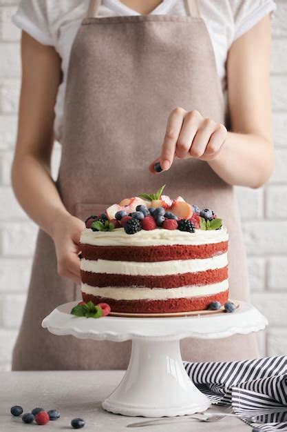 Persona decorando un pastel con frutas