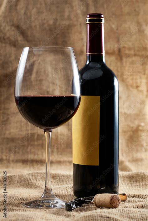 Botella de vino tinto y copa junto a un plato de alubias