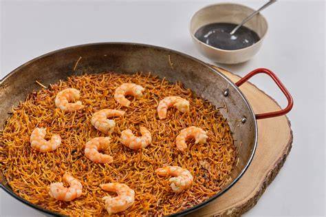 Mesa con fideuá de langostinos recién hecha