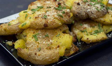 Patatas aplastadas servidas con salsa y queso parmesano