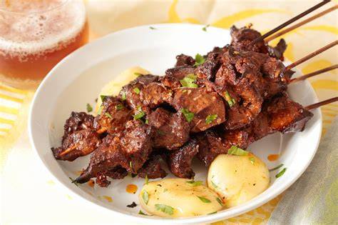 Anticuchos servidos con patatas y salsa criolla