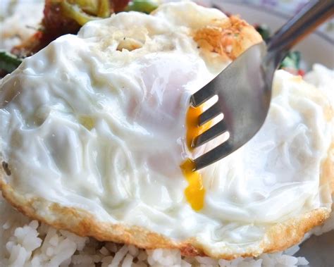 Huevos fritos con yema líquida sobre un guiso de alubias
