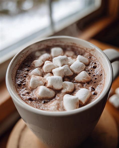 Taza de chocolate caliente con malvaviscos en un ambiente acogedor