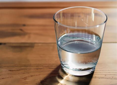 alcachofas frescas sobre una mesa de madera con un vaso de agua
