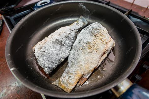 Pescado friéndose en una sartén con aceite caliente