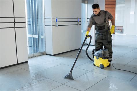 Hombre aspirando el polvo del suelo de azulejos tras una obra