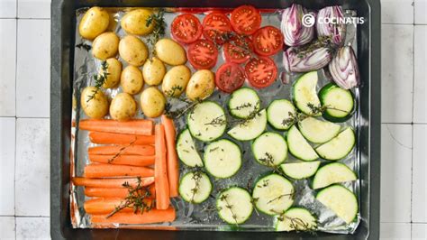 Verduras cortadas y distribuidas uniformemente en una bandeja con papel para hornear