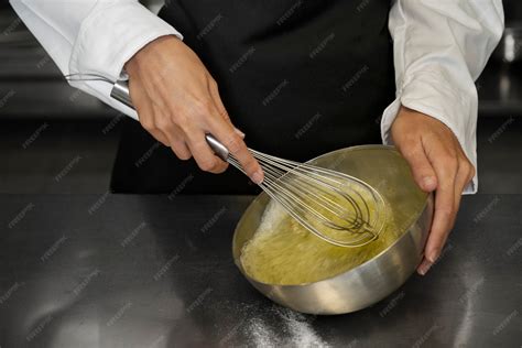 Chef batiendo huevos con una cuchara de metal en un bol