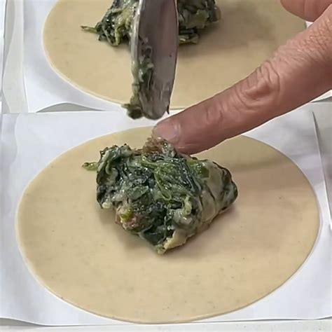 Empanadillas de espinacas y huevo con pasas sobre papel de horno
