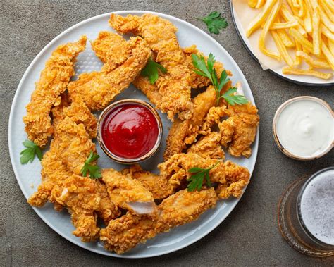 Plato de fingers de pollo saludables al horno con guarnición de verduras