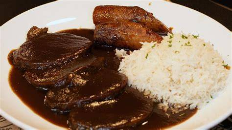 Plato de asado negro servido con arroz y tajadas