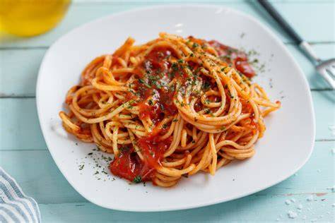 Espagueti con salsa de tomate mezclándose en la sartén