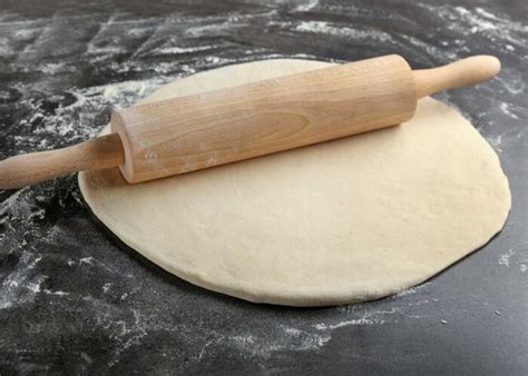 Persona estirando masa de pizza con un rodillo