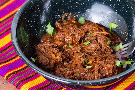 Carne de barbacoa cocinándose en molito de chiles