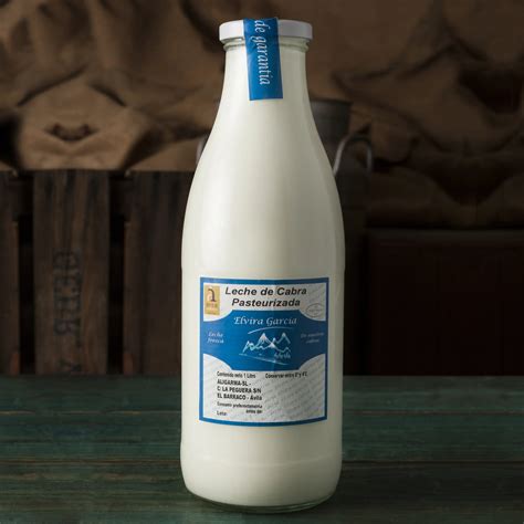 Botella de leche de cabra fresca con cabras en un pastizal de fondo
