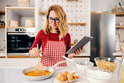 Mujer cocinando con Thermomix y una tableta mostrando una receta