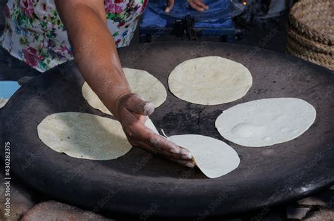 Mujer elaborando tortillas de maíz a mano en un comal